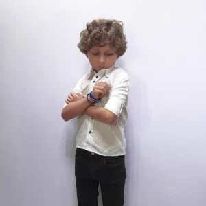 Camisa social kids branca em modelagem semi slim, vestida por menino de braços cruzados
