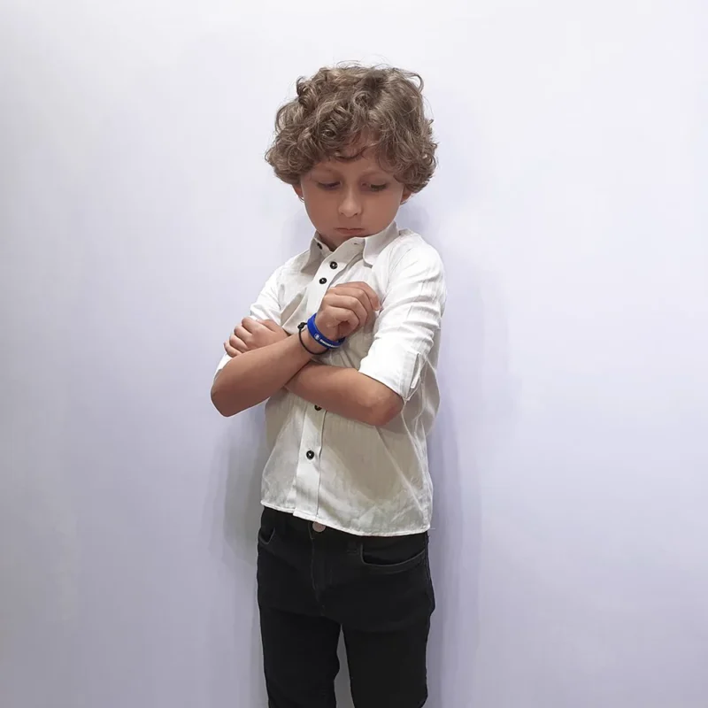 Camisa social kids branca em modelagem semi slim, vestida por menino de braços cruzados