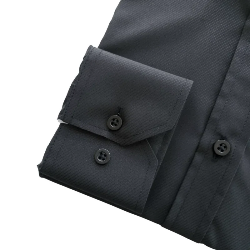 Detalhe do punho de botão da camisa preta, com o relevo do tecido maquinetado