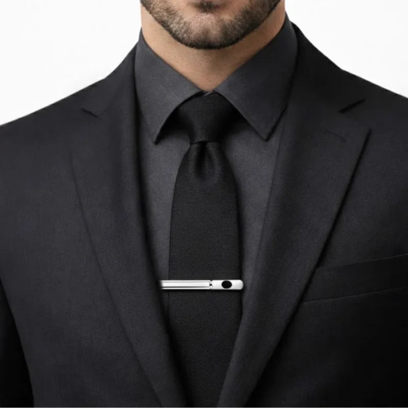Prendedor de gravata prata com detalhe preto preso à gravata preta em traje executivo