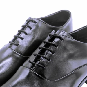 Detalhe do cadarço encerado nos ilhoses e do couro polido do sapato Oxford preto