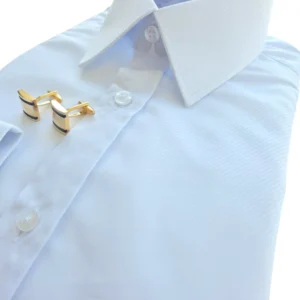 Abotoaduras douradas apoiadas na carcela de botões da camisa branca maquinetada, em vista diagonal